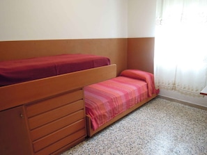 Ein Zimmer mit zwei Etagenbetten, einer Holzkommode und einem Fenster mit Vorhängen.