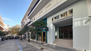 Una calle con una banca, comercios y un edificio con un cartel que dice 'ELITE CENTER'.