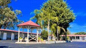 A gazebo with a red roof in front of a building with a red roof. - Seven Inn (Gumly Gumly)