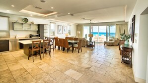 A spacious living area with a dining table, chairs, and a view of the ocean.