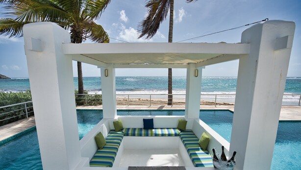 A poolside seating area with a view of the beach and ocean.