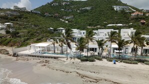 A beachfront hotel with a pool, palm trees, and a view of the ocean.