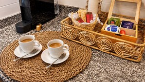 Ein Kaffee-Bereich mit zwei Tassen Kaffee, einer Snack-Korb, einer Blumenvase und einer Holzkiste mit Gegenständen.