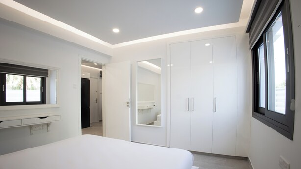Camera moderna con un letto grande, cabina armadio e finestra che lascia entrare luce naturale.