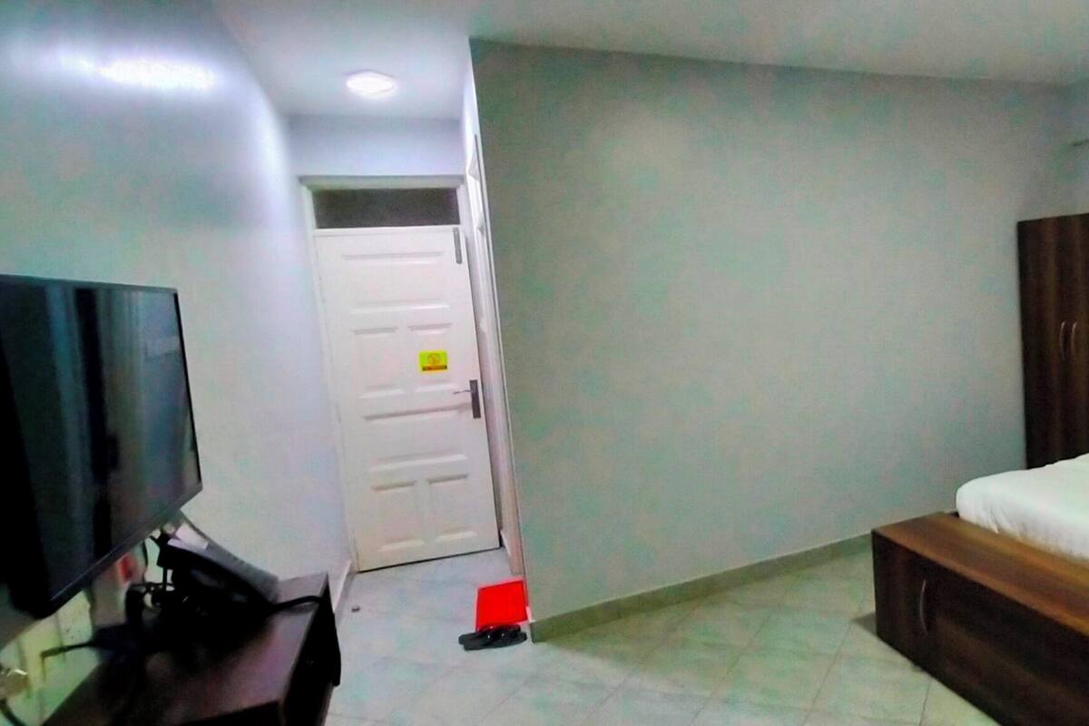 A hotel room with a bed, a TV, a wardrobe, and a door.