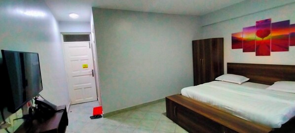 Una habitación de hotel con cama, televisión, armario y puerta.