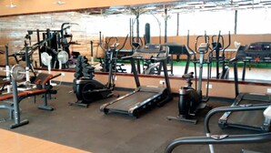 Uma academia com diversos equipamentos de exercício, incluindo esteiras, elípticos e estações de musculação.