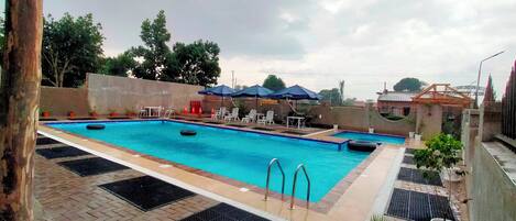 A swimming pool with two lanes, lounge chairs, and umbrellas.