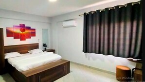 Quarto com cama, guarda-roupa, mesa de cabeceira, abajur e um quadro na parede.
