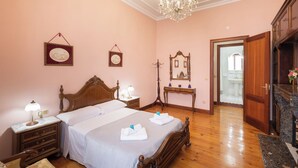A hotel room with a large bed, wooden headboard, bedside tables with lamps, a dresser, a mirror, and a chandelier. - Jauregi - baskeyrentals (Lekeitio)