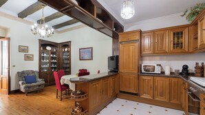 A spacious kitchen with wooden cabinets, a granite countertop, and a dining area with a red chair and a table. - Jauregi - baskeyrentals (Lekeitio)