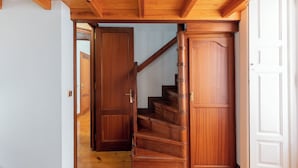 A wooden staircase leading to a second floor, with a door on the right and a partially open door on the left. - Jauregi - baskeyrentals (Lekeitio)