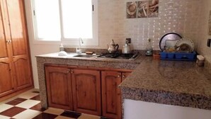 Una cocina con armarios de madera, encimera de granito, suelo a cuadros y una ventana.