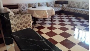 Una sala de estar con piso a cuadros, sofás estampados, una mesa de centro redonda y un detalle de mármol.