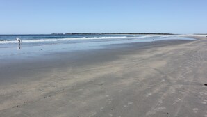 A wide sandy beach with gentle waves and a clear sky. - Cottage at Cherry Hill Beach (Cherry Hill)