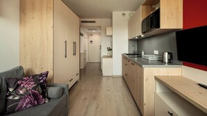 A compact kitchen with wooden cabinets, a grey countertop, and a built-in microwave. - RentPlanet - Apartamenty Dyrekcyjna (Wroclaw)