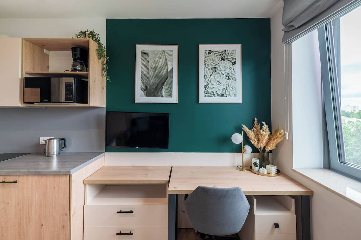 A modern kitchen with a microwave, coffee maker, and a plant on the shelf.