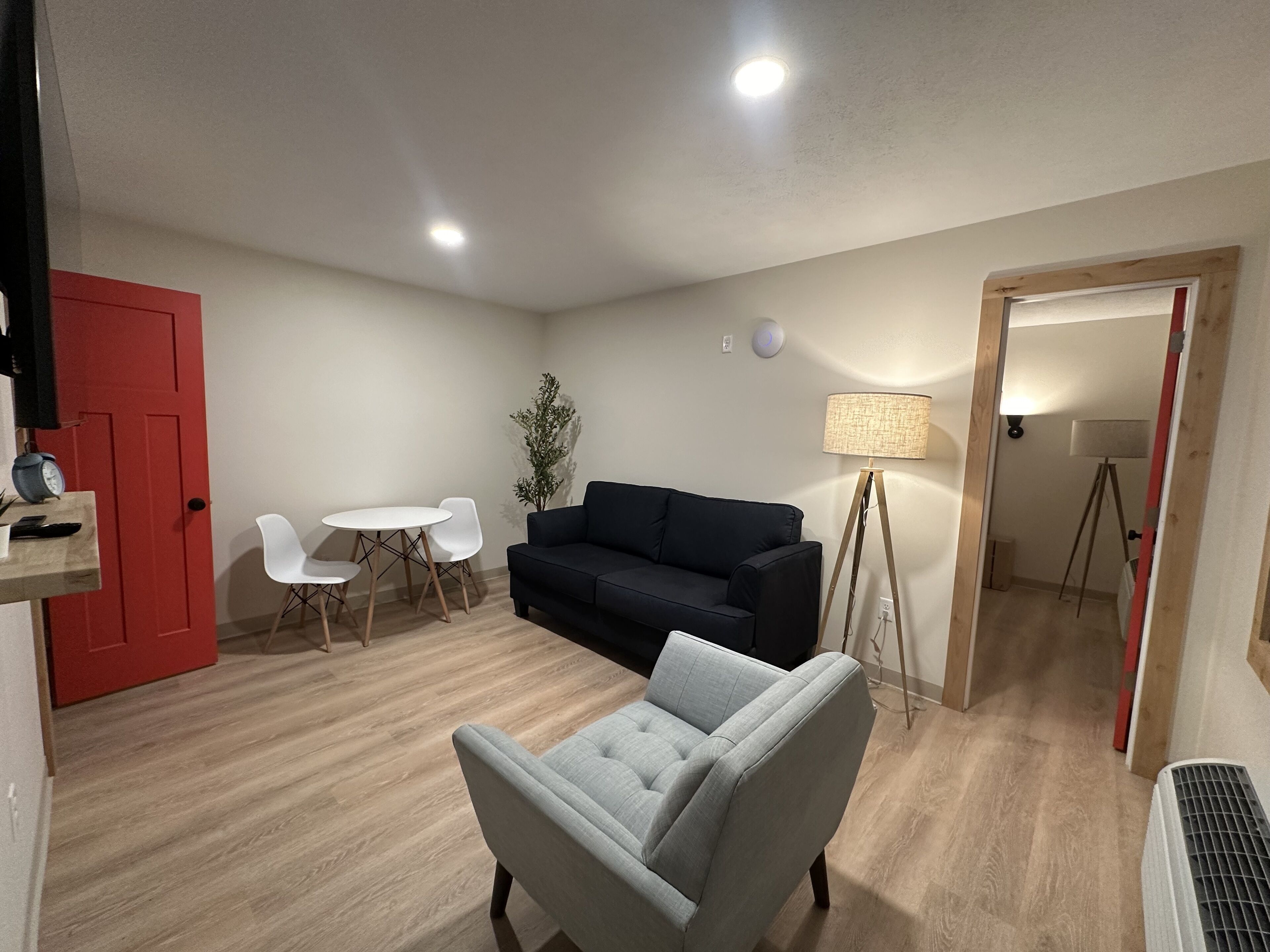 Un salon avec un canapé, un fauteuil, une petite table et une lampe.