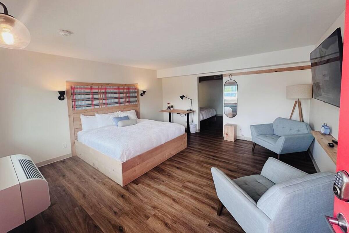 Quarto de hotel moderno com uma cama grande, uma escrivaninha, uma cadeira e uma pequena mesa.