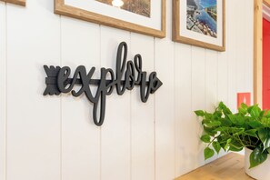 A wall with a black decorative sign spelling "explore" and a potted plant on the right.
