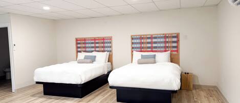 A hotel room with two beds, a wooden headboard, and a light-colored wooden floor.
