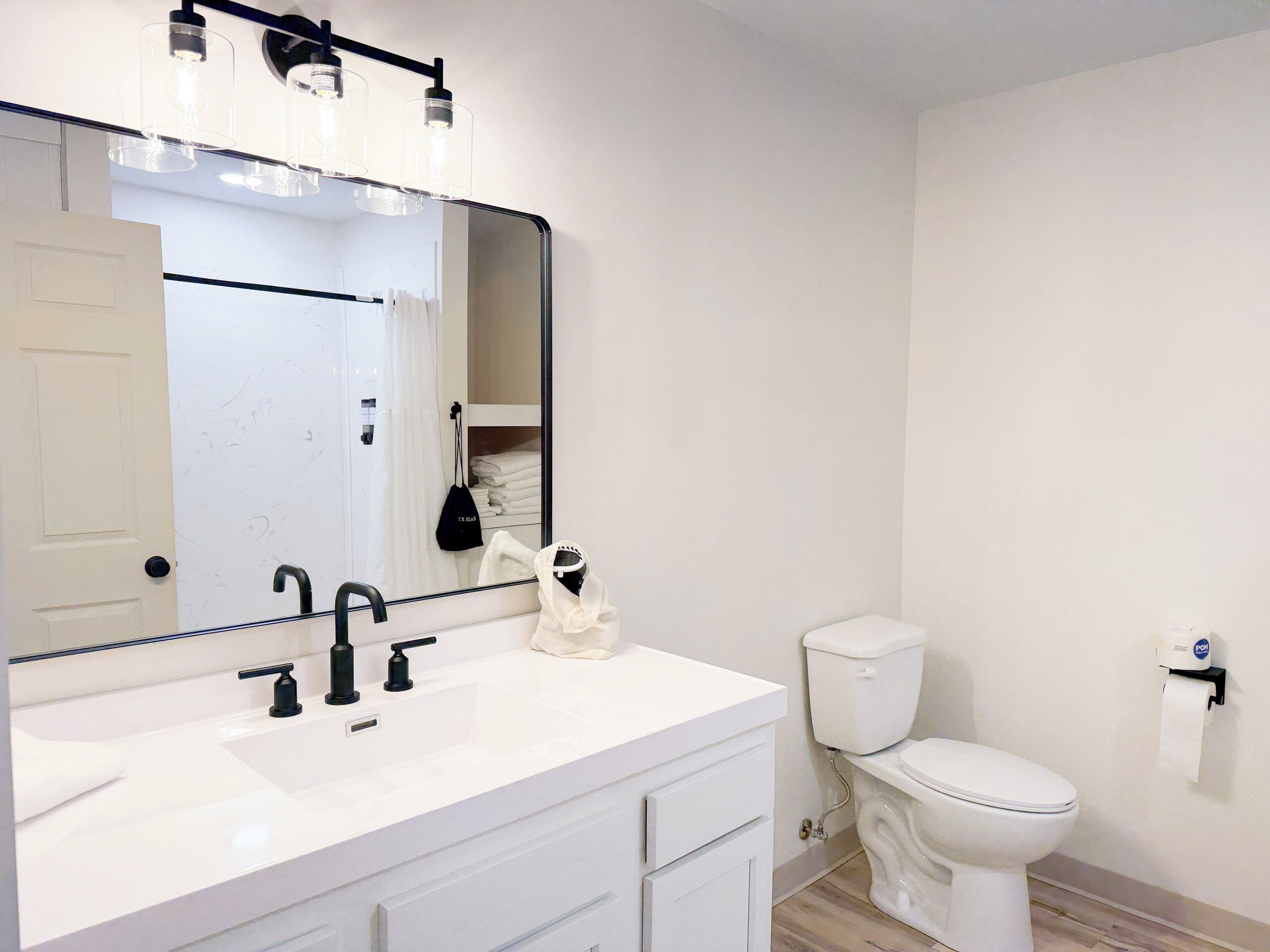 Un baño moderno con un lavamanos blanco, un grifo negro y un espejo grande encima.
