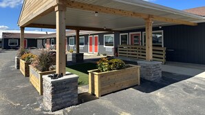 A motel with a covered parking area, wooden benches, and planter boxes with flowers. -  Explorer Rest & Recreation (Sandusky)