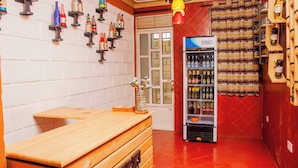 A bar area with a wooden counter, a Solstar refrigerator stocked with beverages, and a wall decorated with bottles and flags. - Jet Villas Entebbe (Entebbe)