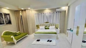 Ein modernes Schlafzimmer mit einem Bett, einem grünen Sofa und einer weißen Kommode.