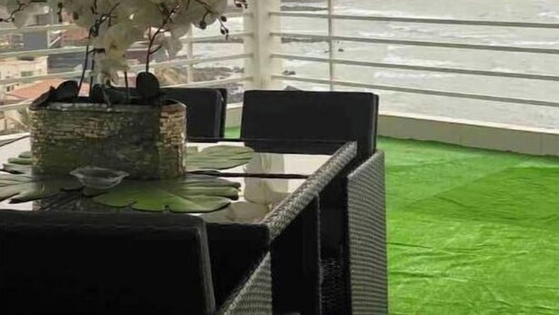 Eine Terrasse mit Tisch und Stühlen, einem Blumentopf und Blick auf eine Stadtlandschaft.