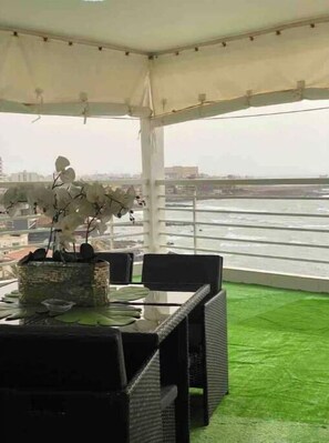 Une terrasse avec une table et des chaises, un pot de fleurs et une vue sur le paysage urbain.