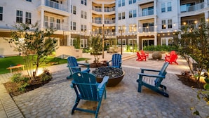 Un patio con mobiliario exterior, una chimenea y un edificio de varios pisos con balcones.