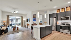 Una cocina moderna con una isla central, electrodomésticos de acero inoxidable e iluminación colgante.