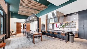 Una cocina moderna con una isla grande, armarios oscuros y una lámpara colgante.