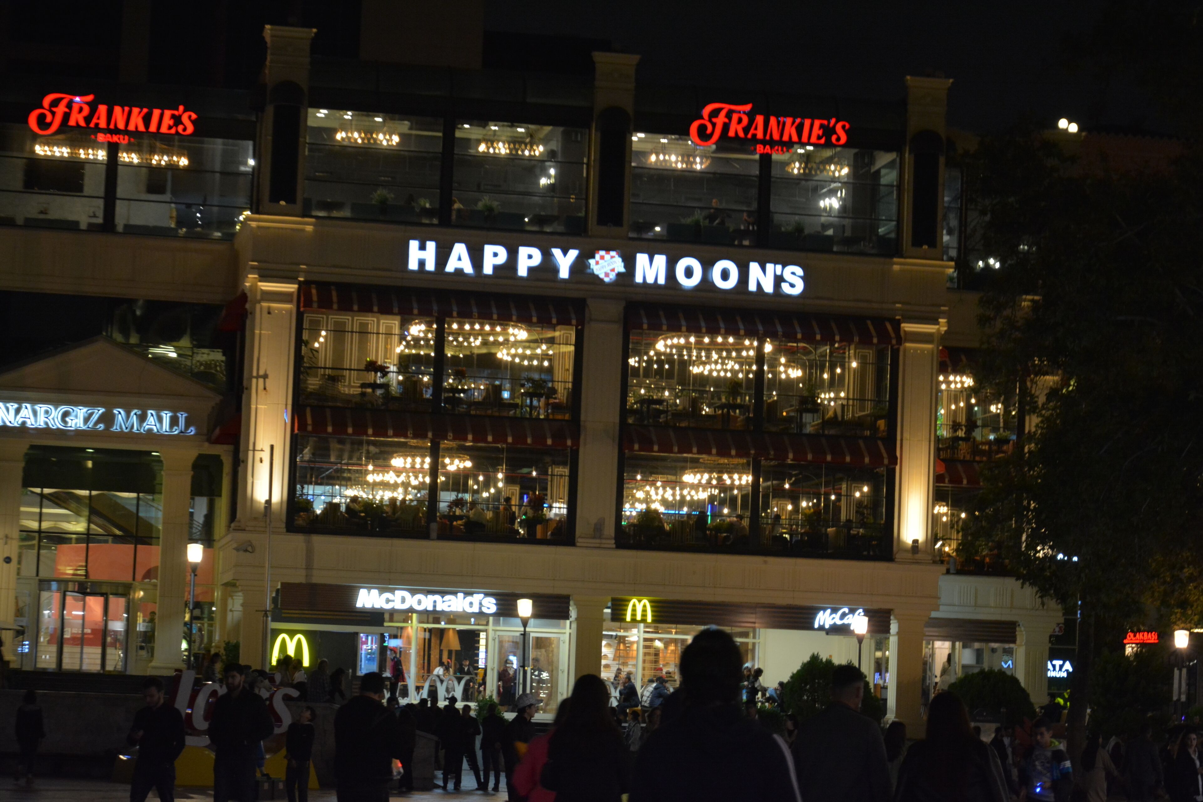 Um edifício de vários andares com a sinalização "HAPPY MOONS" e "FRANKIE'S" no topo.