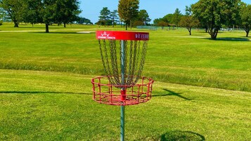 Una canasta de disc golf con estructura roja y un letrero que dice 'DYNAMIC DISCS VETERAN BASKET'.
