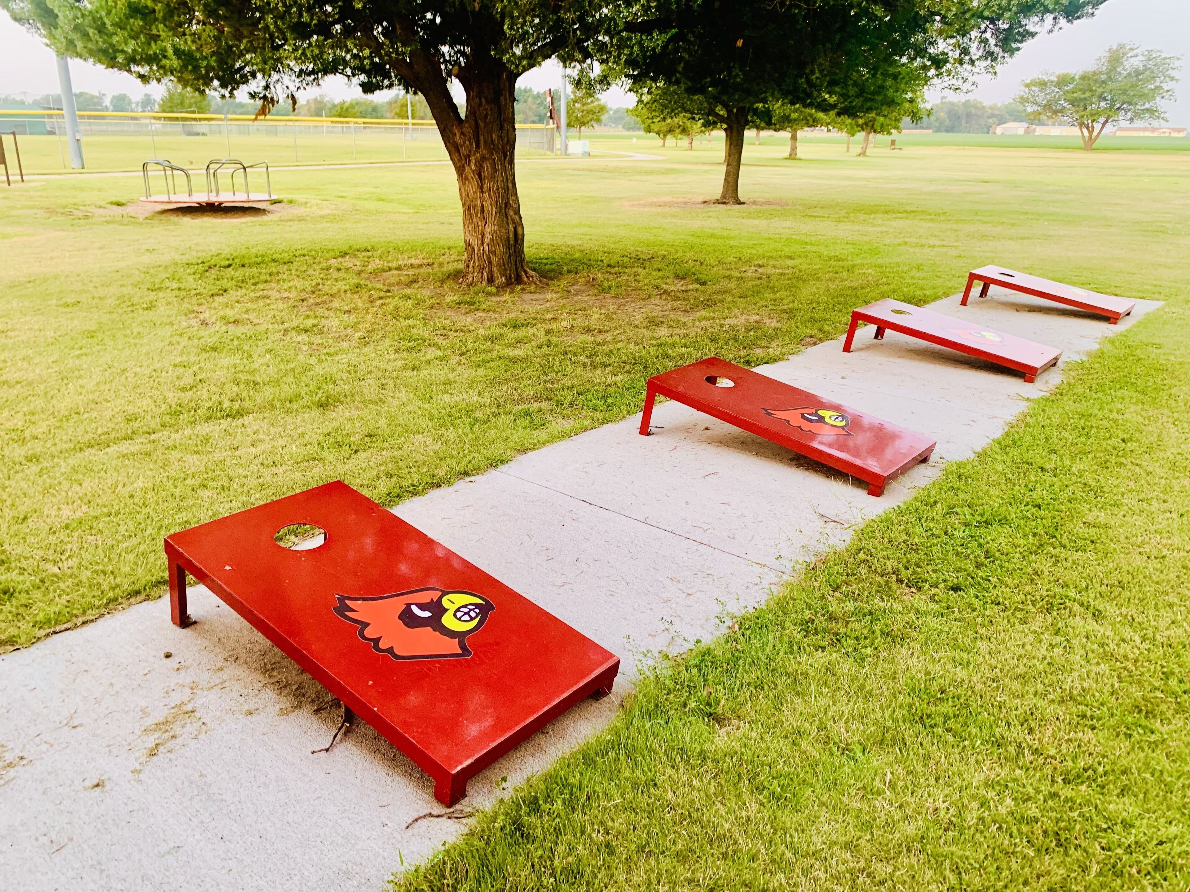 A park with red benches aligned along a concrete path.
