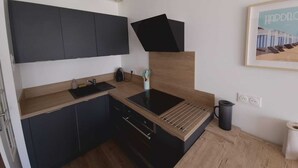 A modern kitchen with dark cabinets, a wooden countertop, a built-in stove, and a hanging light fixture. - Hardelot-Plage - beach - sea view (Neufchâtel-Hardelot)