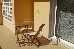 An outdoor seating area with a table and chairs, a door, and a patterned wall. - Marvelous T1 apartment - Cabanas de Tavira (Tavira)