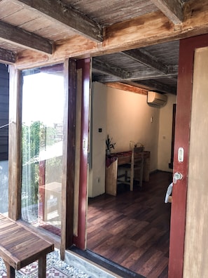A wooden interior with a sliding glass door leading to an outdoor area. - Tree House Lodge (Nusa Dua)