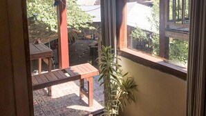 Una habitación de madera con vista a un jardín y un edificio de techos rojos al exterior.