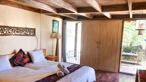 Un dormitorio amplio con una cama grande, vigas de madera en el techo, un armario de madera y vistas al exterior.