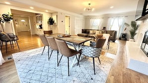 A spacious living area with a dining table, comfortable seating, and a fireplace.