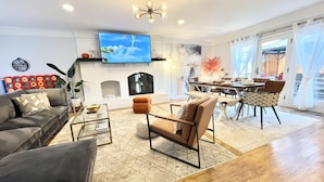 A living room with a fireplace, a dining area, and a TV mounted on the wall.