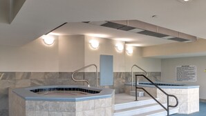Een wellnessruimte met twee whirlpools, een betegelde vloer en een bord met spa-regels.