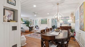 A dining area with a wooden table, chairs, and a chandelier. - Nostalgia of 1930’s with modern kitchen and baths, sleeps 8 (St Simons Island)