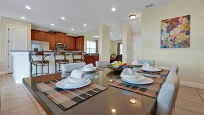 A dining area with a glass table, chairs, and a kitchen in the background. - Reunion Encore Resort Villa W/ Pool Spa Gameroom (kissimmee)