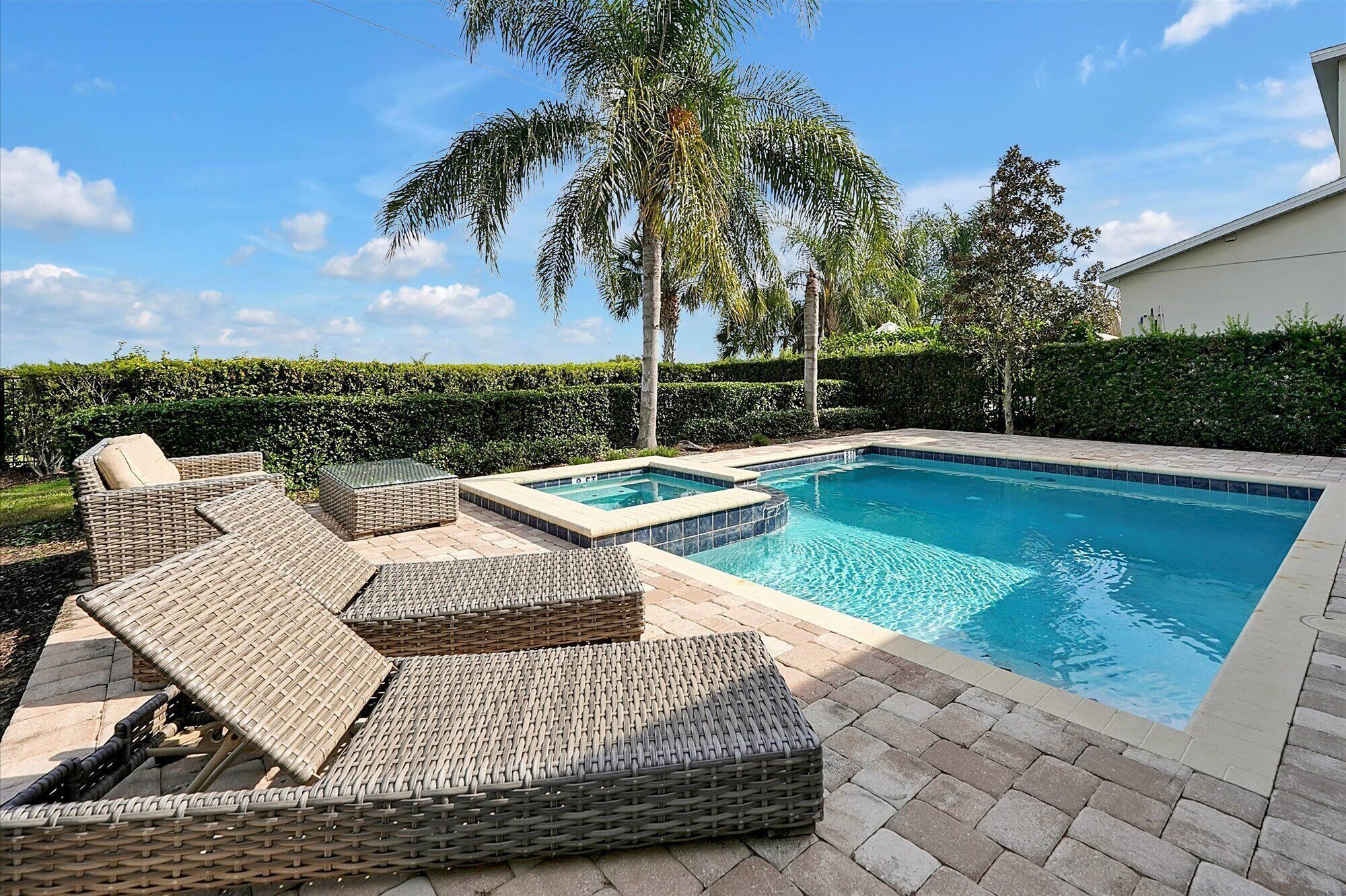 A swimming pool with wicker lounge chairs and a hot tub.