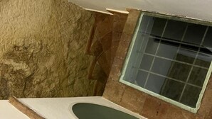 Un bagno con una parete in pietra, una finestra e una vasca da bagno.
