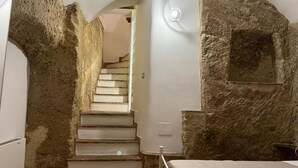 Una scala conduce a una camera da letto con pareti in pietra e un letto.